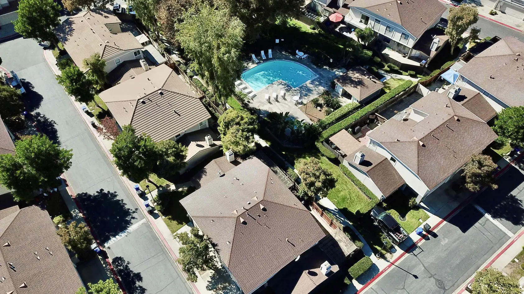 Aerial view of a Rancho Cucamonga HOA community with tile roofs, tree-lined streets, and a shared pool